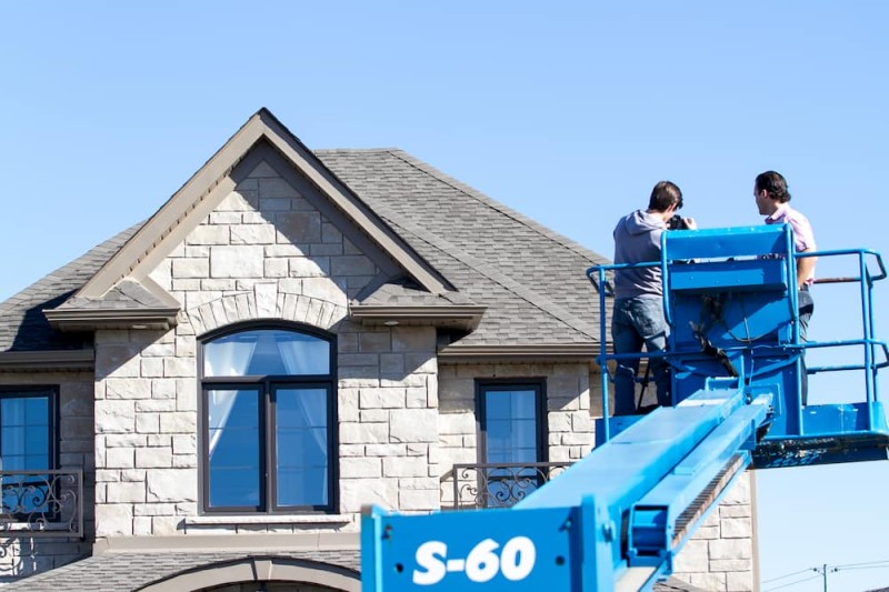 People on blue lift in front of house